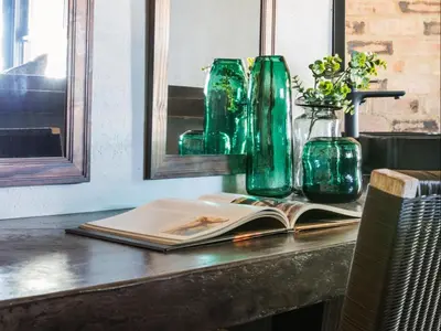 a table with a book and two green glass vases at NAKO Safari Lodge in Dinokeng Game Reserve