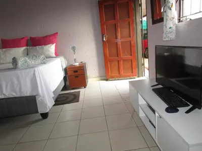 a bedroom with a bed and a flat screen tv at Next to Dinokeng in Hammanskraal Private property in Kekana