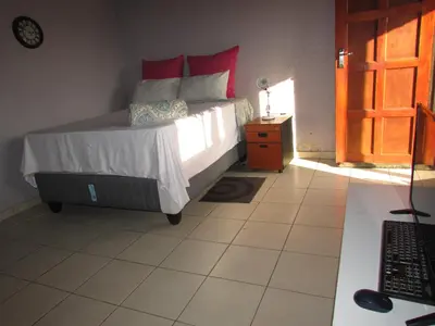 a bedroom with a bed with red pillows on it at Next to Dinokeng in Hammanskraal Private property in Kekana