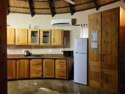a kitchen with wooden cabinets and a white refrigerator at Hardekool Home Marloth Park in Marloth Park