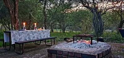 a table and a bench next to a fire pit at Hardekool Home Marloth Park in Marloth Park