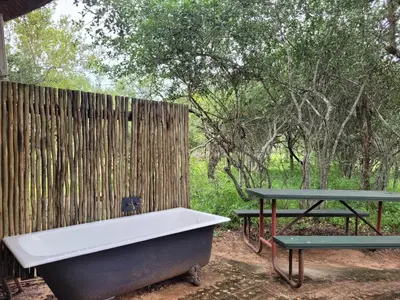 a bath tub and picnic tables next to a fence at Hardekool Home Marloth Park in Marloth Park