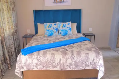 a bed with a blue headboard in a bedroom at Lis ville guest house in Phalaborwa