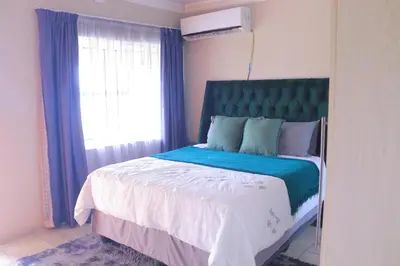 a bedroom with a bed with a blue headboard and a window at Lis ville guest house in Phalaborwa