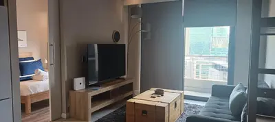 a living room with a blue couch and a television at Menlyn Maine Trilogy Apartment 1010 in Pretoria
