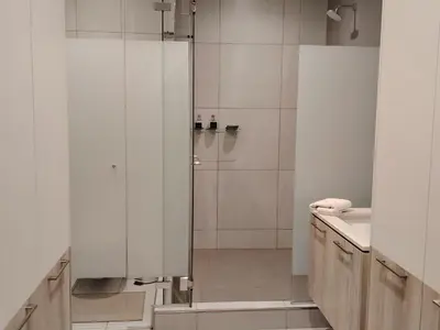 a white bathroom with a shower and a sink at Menlyn Maine Trilogy Apartment 1010 in Pretoria