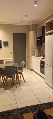 a kitchen with a table and a white refrigerator at Menlyn Maine Trilogy Apartment 1010 in Pretoria