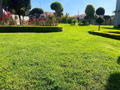 a green lawn with bushes and trees in a park at Siena Sun Luxury Suites in Erand