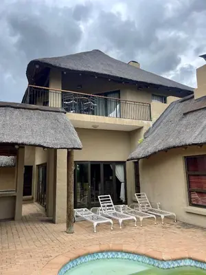 a house with chairs and a pool in front of it at 213 Zebula Golf Estate & Spa - 4 Bedroom Home in Mabula
