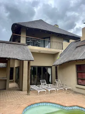 a house with chairs and a pool in front of it at 213 Zebula Golf Estate & Spa - 4 Bedroom Home in Mabula