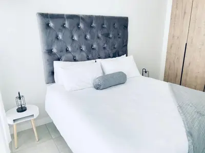 a bedroom with a white bed with a black headboard at The Blyde Crystal Lagoon Bliss in Pretoria