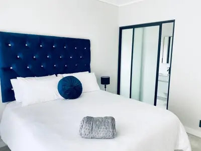 a bedroom with a large white bed with a blue headboard at The Blyde Crystal Lagoon Bliss in Pretoria