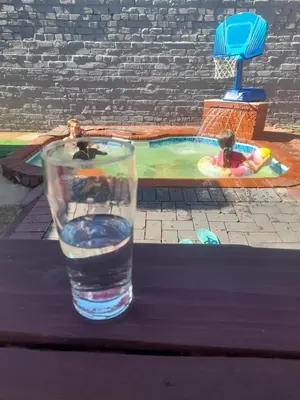 a glass of water sitting on a table next to a swimming pool at Cozy guesthouse springs in Springs