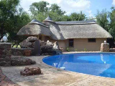 a house with a thatched roof and a swimming pool at Sambane Game Lodge in Bracondale