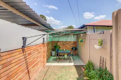 a small backyard with a table and a fence at Ovendales Self Catering Cottage in Benoni