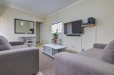 a living room with two couches and a flat screen tv at Ovendales Self Catering Cottage in Benoni