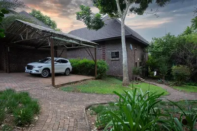 a white car parked in front of a house at Hippo Hills Lodge Ngwenya in Marloth Park