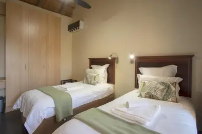 a bedroom with two beds with white sheets at Hippo Hills Lodge Ngwenya in Marloth Park