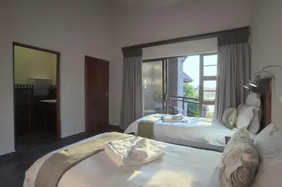 a bedroom with two beds and a large window at Hippo Hills Lodge Ngwenya in Marloth Park
