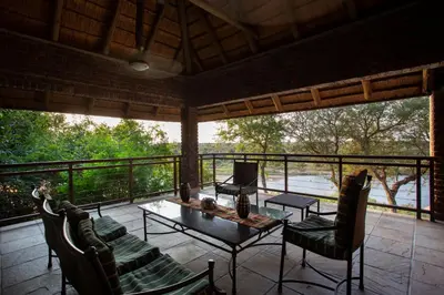 a screened in porch with a table and chairs at Hippo Hills Lodge Ngwenya in Marloth Park