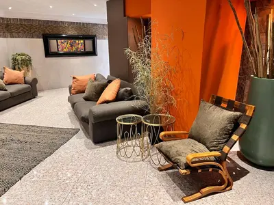a living room with a couch and two chairs at Solitaire Guest Apartments in Pretoria