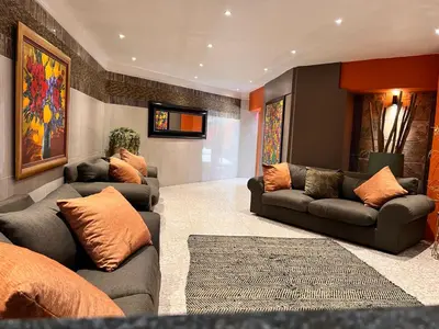 a living room with two couches and a television at Solitaire Guest Apartments in Pretoria