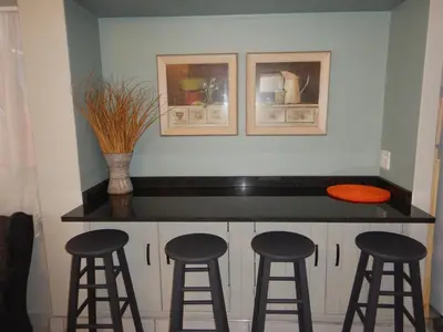 a kitchen with three bar stools and a counter top at Solitaire Guest Apartments in Pretoria