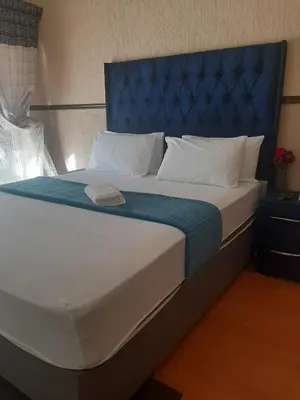 a large bed with a blue headboard and white pillows at Brovad Guesthouse in Kempton Park