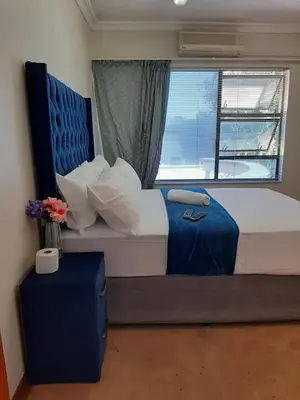 a bedroom with a large bed with a window at Brovad Guesthouse in Kempton Park