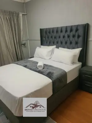 a bedroom with a bed with a black headboard at Brovad Guesthouse in Kempton Park