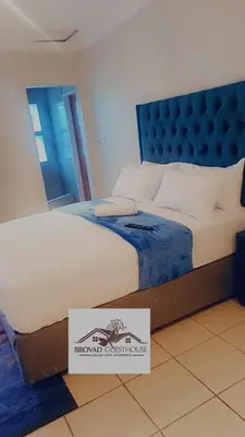 a bedroom with a bed with a sign on the floor at Brovad Guesthouse in Kempton Park