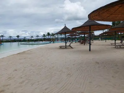 a beach with chairs and umbrellas and the water at Craiden Holiday Apartment at The Blyde Crystal Lagoon 2 bedrooms in Pretoria