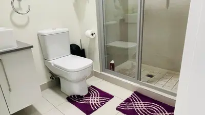a bathroom with a toilet and a shower and purple rugs at 92 On New By Damo in Midrand