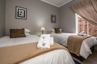 a bedroom with three beds and a window at Dew Drop Inn in Nelspruit