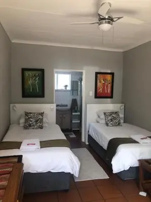 a bedroom with two beds and a ceiling fan at Dew Drop Inn in Nelspruit
