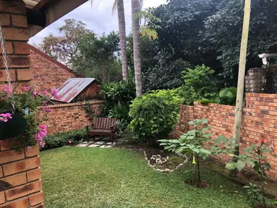 a garden with a bench and a brick wall at Dew Drop Inn in Nelspruit