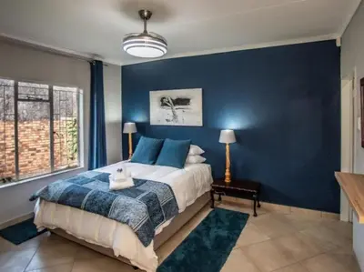 a bedroom with a large bed with blue walls at Dew Drop Inn in Nelspruit