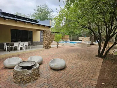 a house with a brick patio with a swimming pool at Marloth Cottage in Marloth Park