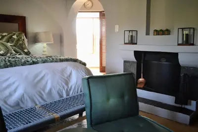 a bedroom with a bed and a chair and a fireplace at Cherry Grove 2 in Dullstroom