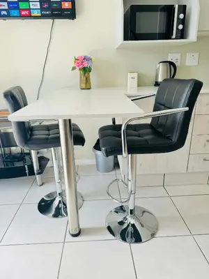 a white table with black chairs in a kitchen at Gallagher Midrand BnB in Midrand