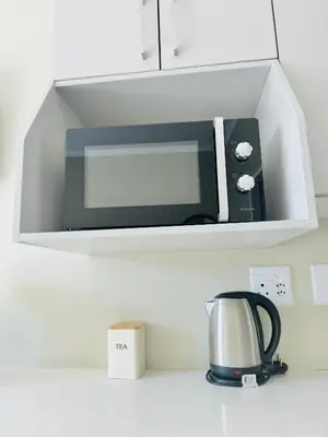 a microwave on a shelf above a kitchen counter at Gallagher Midrand BnB in Midrand