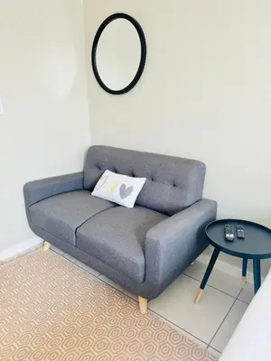 a gray couch in a living room with a mirror at Gallagher Midrand BnB in Midrand