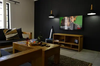 a living room with a couch and a tv on a wall at Zebra Cottage in Pretoria