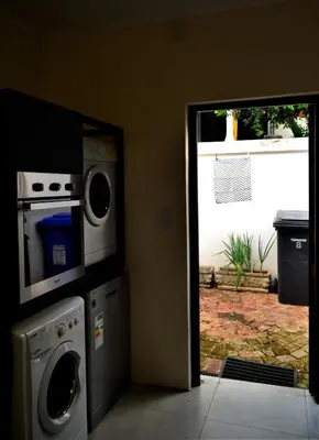 a kitchen with a washing machine and a microwave at Zebra Cottage in Pretoria