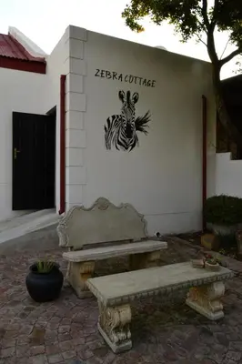 a bench in front of a building with a zebra caricature at Zebra Cottage in Pretoria