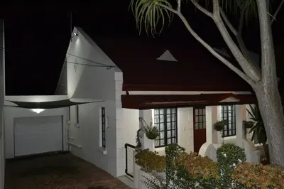 a white house with a garage at night at Zebra Cottage in Pretoria
