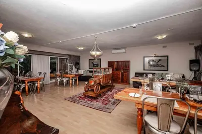 a large living room with tables and chairs at The Green Lizard Guesthouse in Nelspruit