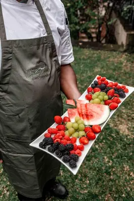 a man holding a tray of fruit on a plate at The Green Lizard Guesthouse in Nelspruit