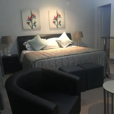 a bedroom with a bed with a chair and a couch at Lesolo Lodge in Burgersfort