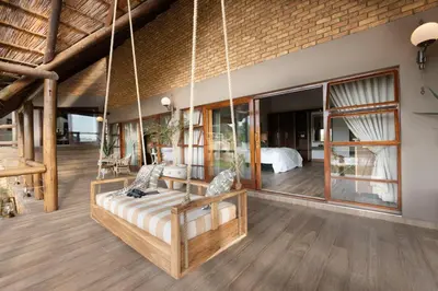 a room with a suspended couch and a bed at Kingfisher Villa in Mabula Game Reserve in Mabula